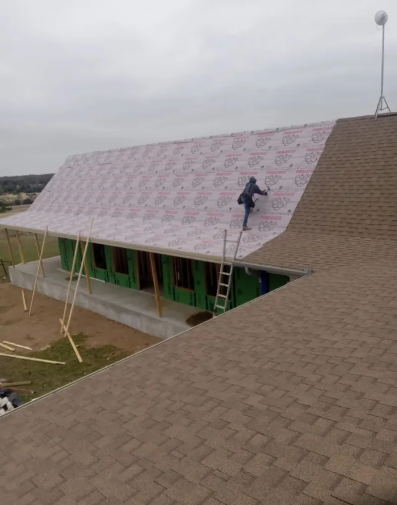 Worker preparing underlayment for a metal roof installation in Mokena